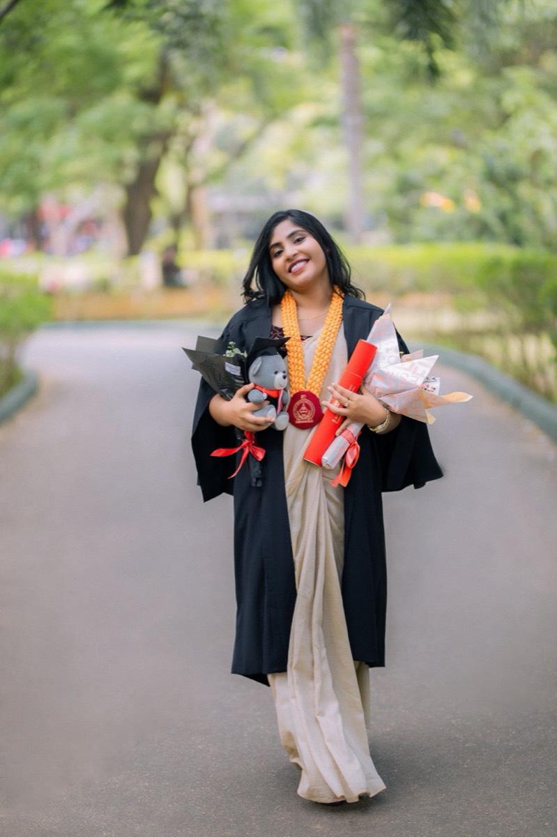 A smiling graduate in a saree and gown holding her degree, Mihintale
